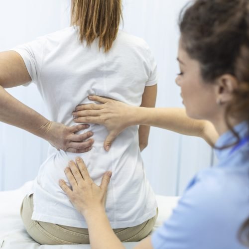 Physiotherapist doing healing treatment on womans back. Back pain patient, treatment, medical doctor, massage therapist.office syndrome Physiotherapist doing healing treatment on womans back. Back pain patient, treatment, medical doctor, massage therapist.office syndrome